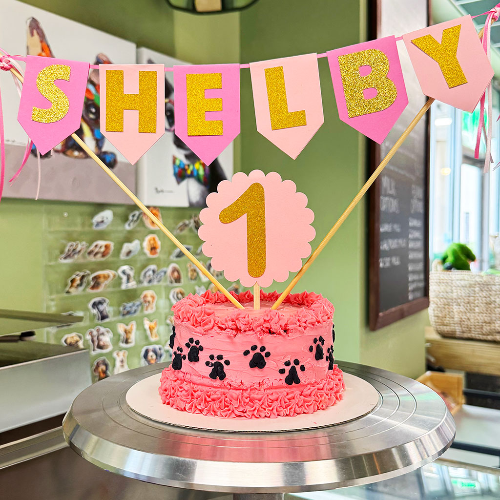 First birthday dog cake with paw print design and personalized age topper